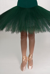 Legs of ballerina and a green tutu on a white background