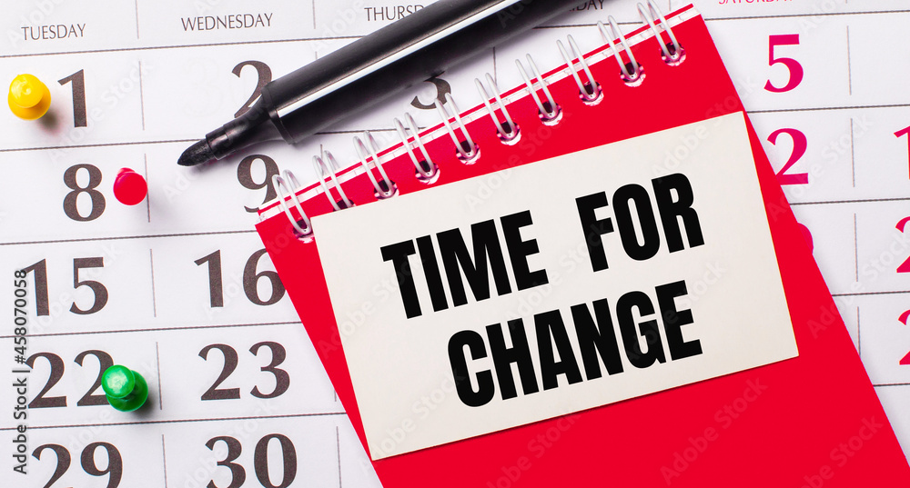 Poster on the calendar is a white card with the text time for change. nearby is a red notepad and a marker.