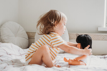 Toddler girl playing with her doll at home