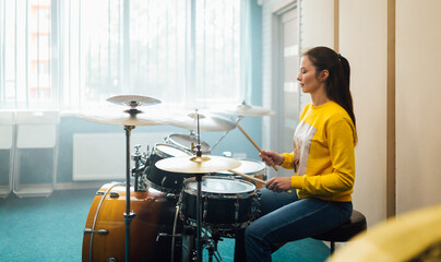 Fototapeta na wymiar Young girl practicing drumming on drum set