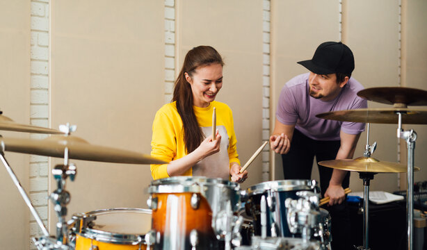 Man instructor teaching female drummer in class.