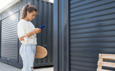 Young skater girl checking her cell phone in the city