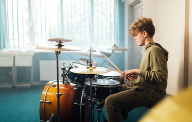 Boy musician behind a drum kit. - obrazy, fototapety, plakaty