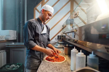 Tuinposter The chef prepares pizza. Catering kitchen work. © Аrtranq
