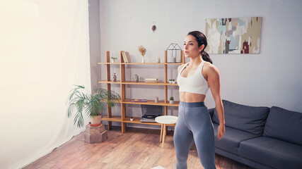 Fit sportswoman looking away in living room