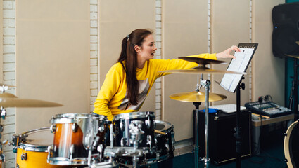 Young woman flipping notes for drumming. Lesson at the drum music school.