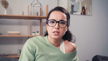 Focused woman in eyeglasses looking at camera at home