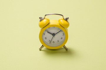 Yellow alarm clock on a green background. Copy space.
