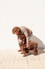 middle-aged man and dog, both with curly hair loving each other