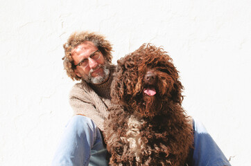 large dog with curly and red hair looking at camera and panting, behind him is his owner, a middle-aged man with curly hair and glasses