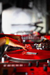 Dj girl playing music with turntables on scene in night club. Professional disc jockey woman mixing musical tracks with sound mixer and turn table in red stage lights