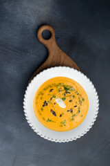Pumpkin soup in a plate on a gray background.