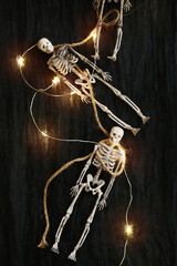 Halloween decorations, two toy skeletons with light garland on black fabric