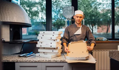 Poster Pizzeria worker building pizza packaging. Catering kitchen work. © Аrtranq