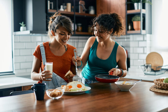 Young happy female friends have breakfast together at dining table. - Powered by Adobe