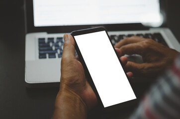 hand holding phone mockup image blank screen computer laptop for advertising text in workplace desk at office.