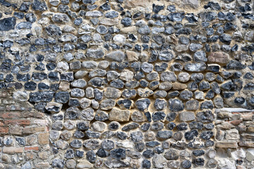 sehr alte Steinmauer mit Kies und anderen Steinen / Hintergrund / Texturen