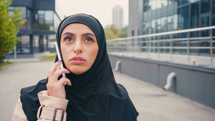 Young muslim woman in hijab having phone call outside