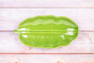 A ceramic green empty dish designed as a banana leaf on wood table