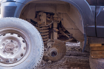 A broken wheel stands next to a car.