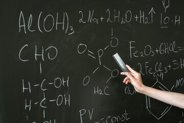 female teacher explane chemical formulas near chalkboard