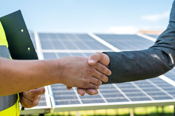 Male handshakes close up against solar panels .