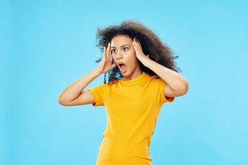 emotional woman with curly hair in a yellow t-shirt blue background