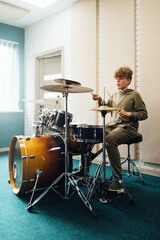 The boy at the drum set plays energetic.