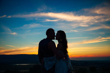 Silhouette of a couple hugging and kissing at sunset against the background of mountains and sea