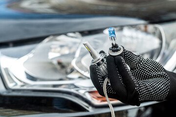 The mechanic's hands hold two diferent car bulbs for replacement in car