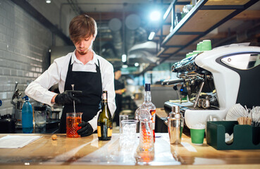 Barman stirring the cocktail with a bar spoon. Drink preparation process.