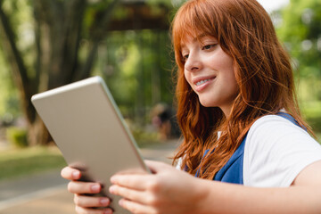 Smart young caucasian woman girl teenager student using digital tablet, surfing Internet, posting...