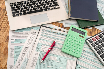 Obraz premium on a wooden table lie a laptop, American tax forms with a tablet and a pen