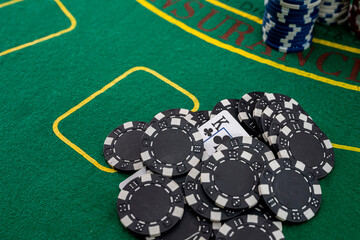 a pile of black chips lie on a green poker table