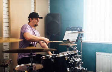 The guy learns how to play the drums from the notes. Playing musical instruments.
