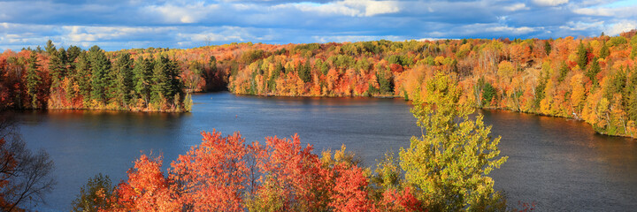 Bright fall foliage along scenic Saint Maurice river in Quebec.