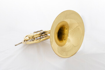 A shiny lacquered French horn in a white box