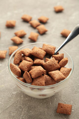 Bowl with chocolate pads on grey background.