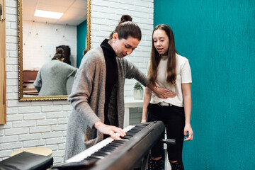 Woman teaching her student to sing while accompanementing on electronic piano