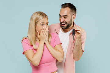 Young surprised happy couple two friends family man woman in casual clothes together make surprise gift car key isolated on pastel plain light blue background studio portrait People lifestyle concept.