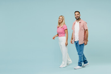 Fototapeta premium Full body young couple smiling fun two friends family man woman in casual clothes look camera walk go together isolated on pastel plain light blue background studio portrait People lifestyle concept