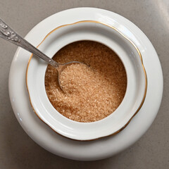 Cane sugar in a porcelain sugar bowl with a spoon
