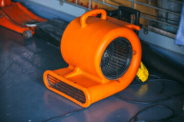 Orange blower fan machine on wet floor. Heavy Duty Industrial Portable Blower Fan on floor 
Used to reduce heat to racing cars.