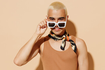 Young smiling trendy fashionable stylish blond latin gay man in beige tank shirt neck scarf take...