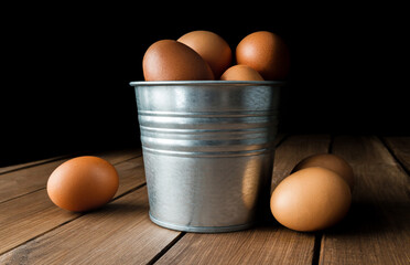 Fresh eggs inside small tin bucket, pail or metal container. Composition on wooden table.