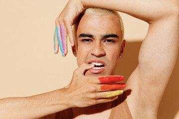 Young sexy trendy blond latin gay man 20s with make up fingers painted in rainbow flag colors...