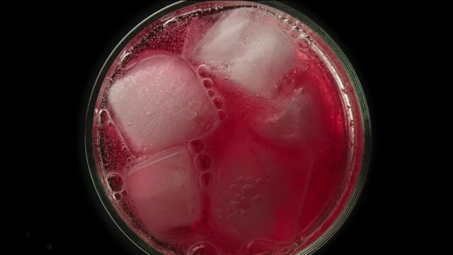 Raspberry lemonade in a glass with ice bubbles on a dark background