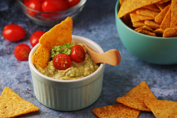 Homemade guacamole with corn chips and cherry tomatoes