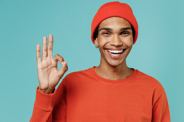 Young smiling happy satisfied cheerful cool fun african american man in red shirt hat showing okay...