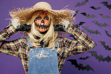 Young woman with Halloween makeup mask in straw hat costume cover ears with hands finger do not want to listen scream isolated on plain dark purple background studio Celebration holiday party concept